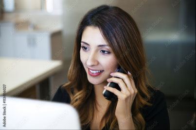 Woman on a mobile sat at the computer